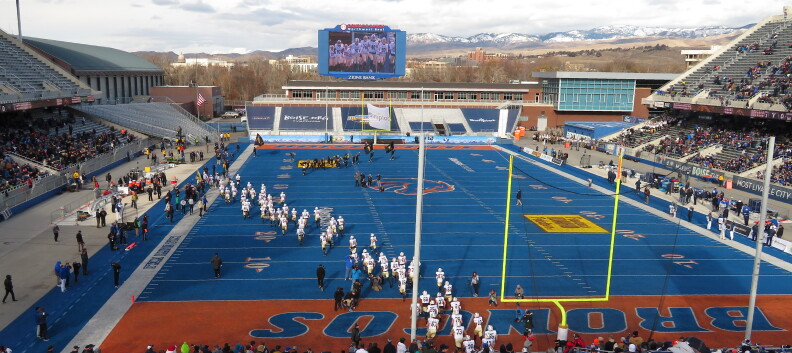 Football players walk across the Boise State University blue turf.