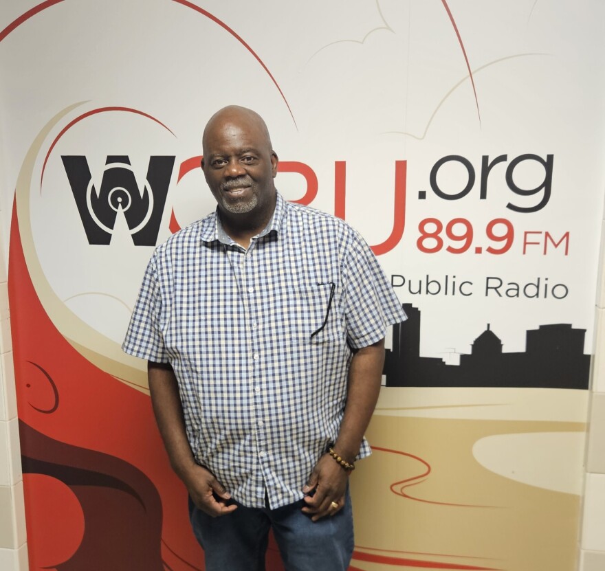 A man poses for a photo in front of a WCBU wall sign