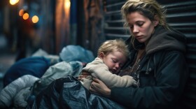 A homeless mother with her baby on a city street at night. 