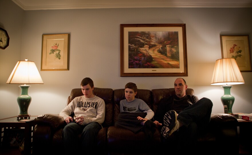 Brian Jordan checks his iPhone while Kevin and their father watch television.