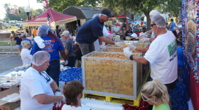 Volunteers fill containers with banana pudding for waiting festival goers