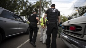 In this July 8, 2019, photo, a U.S. Immigration and Customs Enforcement (ICE) officers escort a man in handcuffs during an operation in Escondido, Calif. 