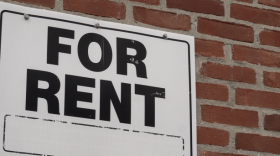 A "For Rent" sign on a brick wall