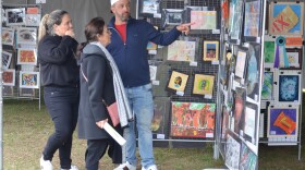 Man points to art displayed at the 2023 Winter Park Sidewalk Arts Festival