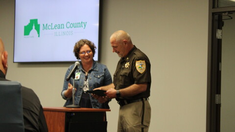 A police officer and a lady stand at a podium. 