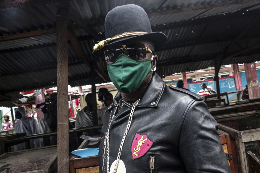 A <em>Sapeur</em> — as Congolese fashionistas are known — shows off his mask at a market in Kinshasha.