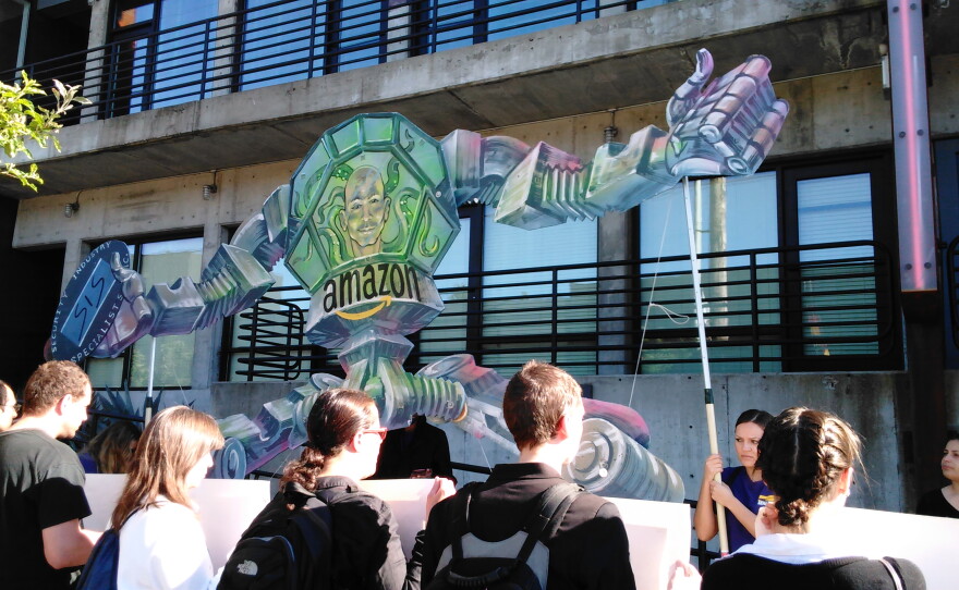 Protesters outside Amazon's annual shareholder's meeting hold up a RoboBezos sign