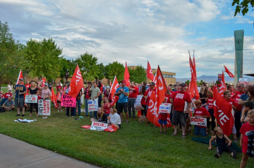 A photo of people gathered at a protest with Dixie flags and signs.