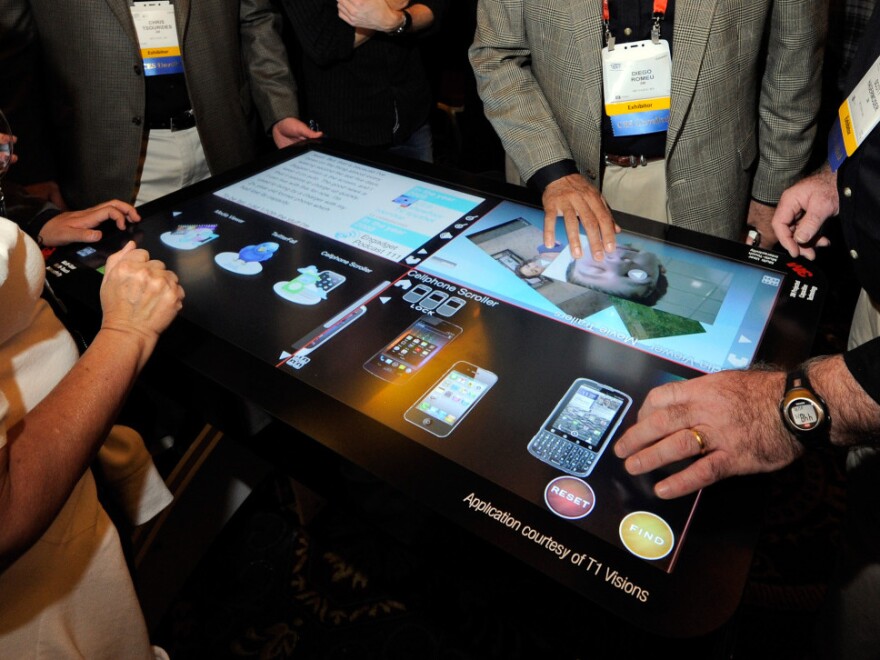 Attendees try a prototype 3M Touch Systems projected capacitive display at the Consumer Electronics Show in Las Vegas. Analysts say the way we interact with computers and other devices will be radically different in a few decades.