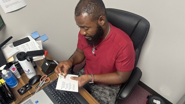 Image, brown skinned man putting picture into passport holder.