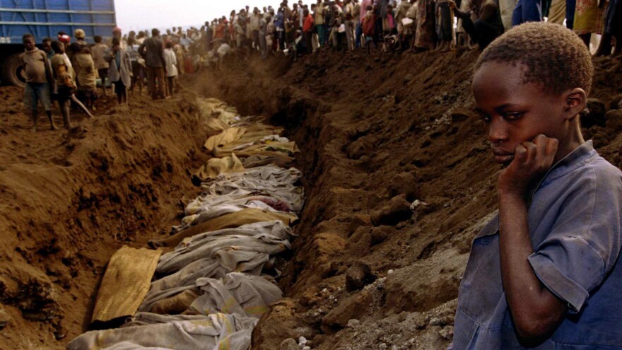 A Rwandan refugee girl stares at a mass grave where dozens of bodies were laid to rest in July 1994.