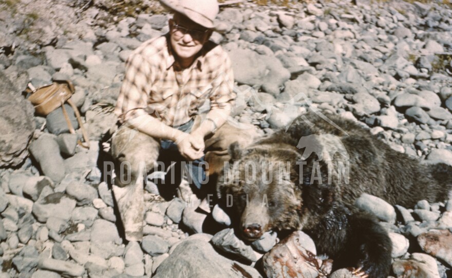 Another hunter sits next to a dead grizzly bear near Yellowstone National Park.