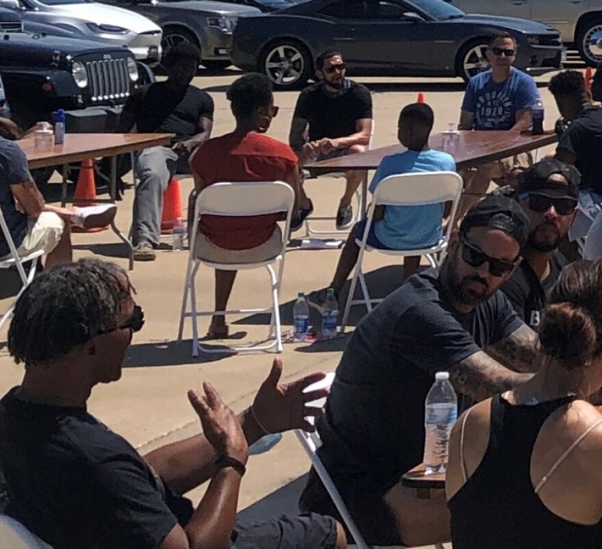 people talking at tables in a parking lot