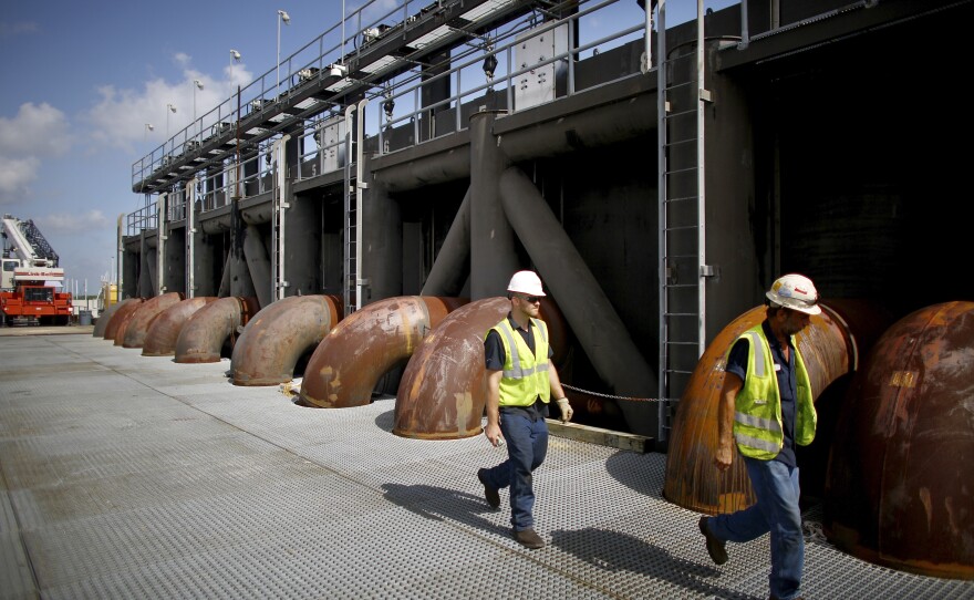 Maintenance crews walk across the flood gate and pumping station at the 17th Street Canal in New Orleans. The existing pump station will be replaced with a new flood protection barrier and pump house that's still under construction.