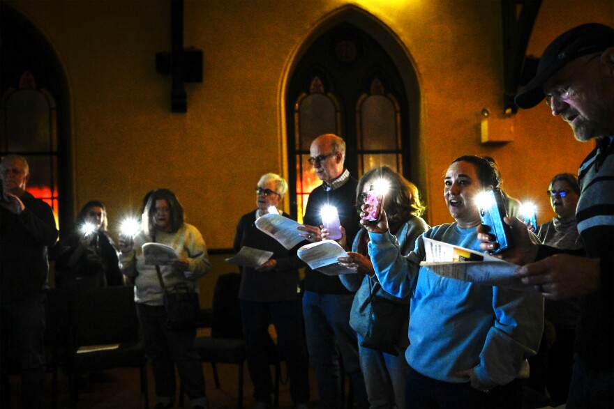 Audience members at a “teach in” at the Unitarian Universalist Congregation in Stamford turn their phone flashlights on to practice performing protest songs as part of a weekly protest against federal deportation efforts on 2/11/26.