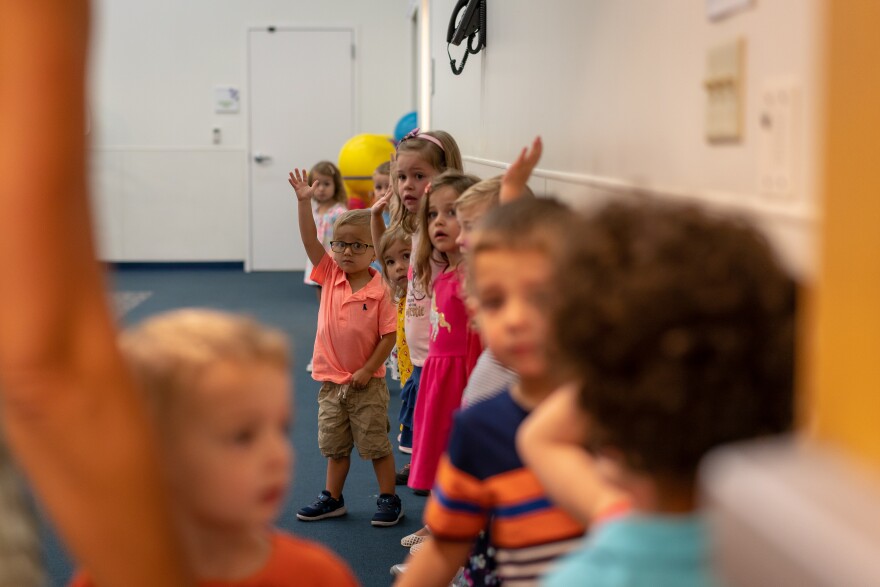 Children wait in line to grab their backpacks and find their classrooms during the first day of school at the Affton preschool center.