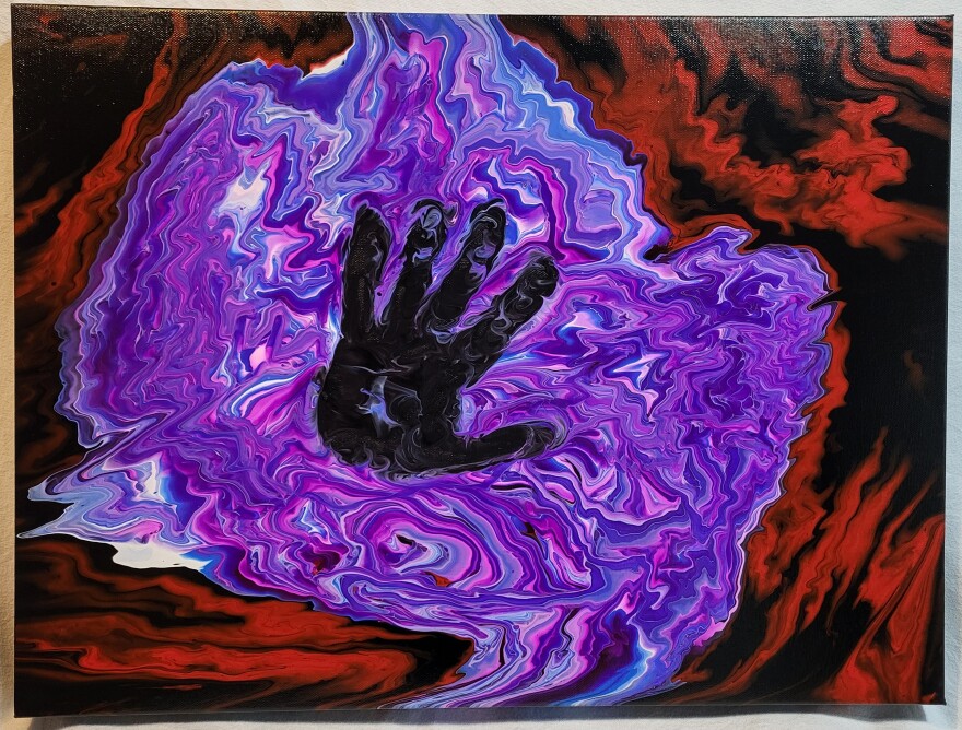 An acryclic pouring painting with a red and black background and a bright purple puddle with a handprint on top.