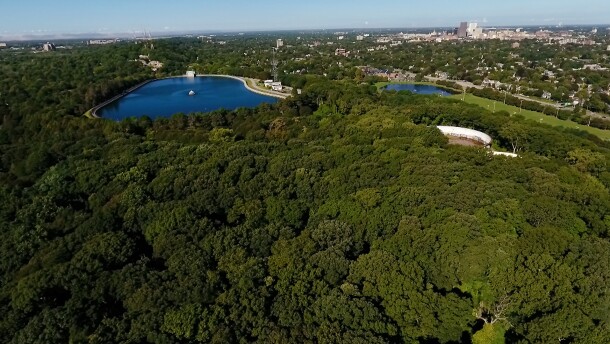 An aerial view shows Washington Grove and Cobbs Hill park and reservoir with the Rochester skyline in the distance.