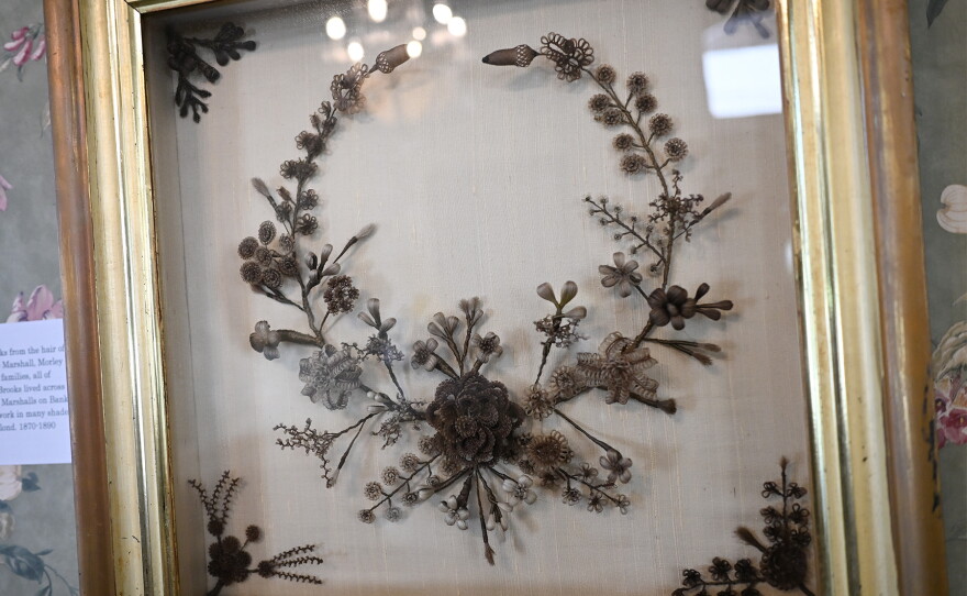 A gold frame holding a wreath hand made with human hair