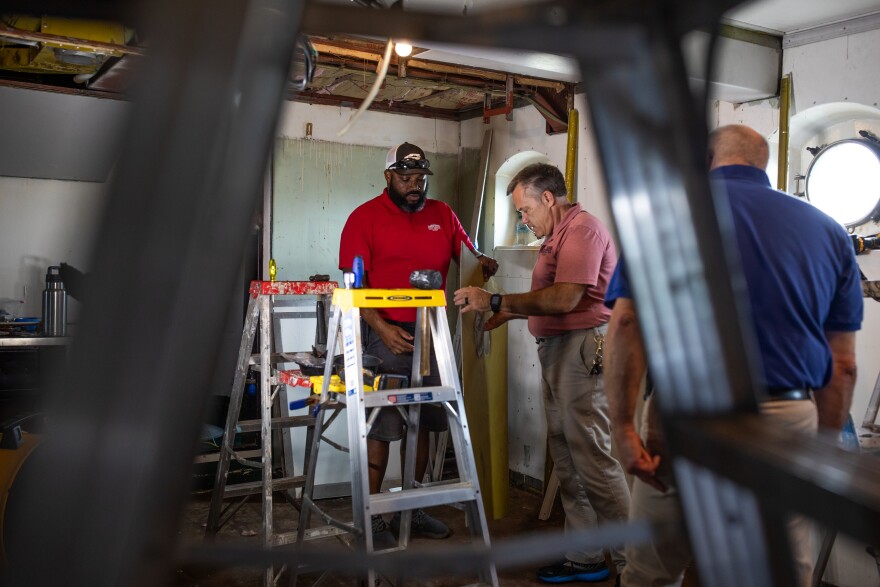 Jason Robbins, left, a Maintenance Tech 3, and Terry Kuhn, right, the ship's Maintenance Director of 33 years, work on replacing steel panels in the Admiral's Cabin on board the Battleship North Carolina on August 14, 2025. Previous repairs had patched problem areas with lower quality steel, but Executive Director Dr. Jay Martin is committed to using higher quality, thicker steel that matches the original specs of the ship as closely as possible. As Dr. Martin explains, on a ship like the Battleship North Carolina, "steel is sacred." The Battleship funds its repairs through admission and donations as they look to the ship's 100th anniversary in 2037.