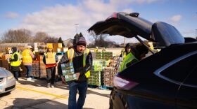 Food Bank volunteers load cars with groceries at mobile food pop-up distribution.