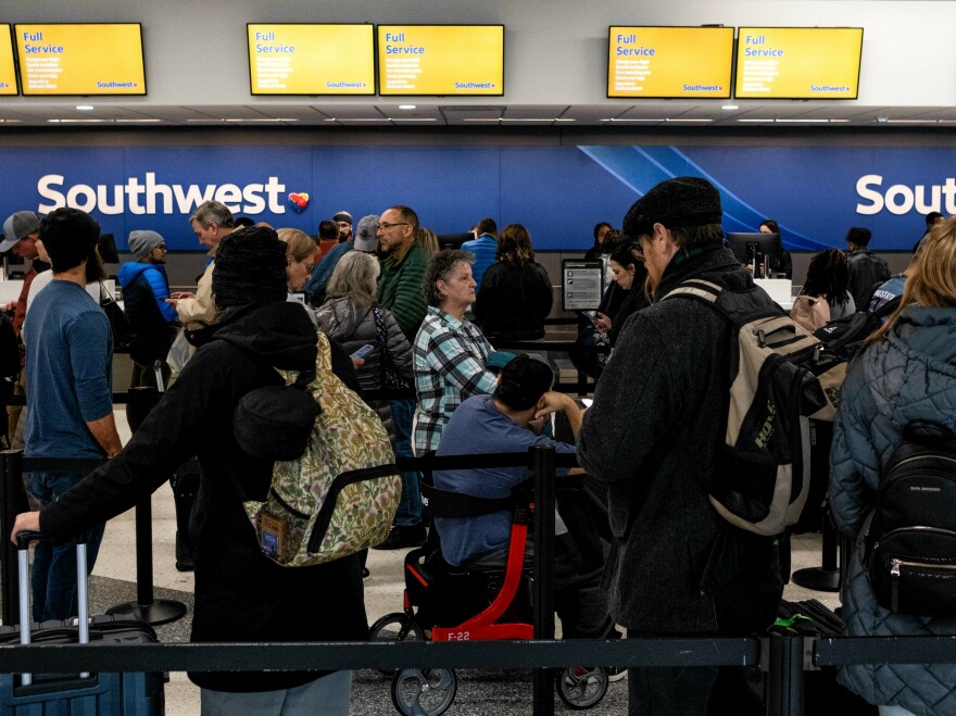 Travelers wait in line at the Southwest Airlines ticketing counter at Nashville International Airport after the airline cancelled thousands of flights on Tuesday.