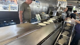 Tortillas being rolled out on a conveyor belt from a machine, alongside workers at Tortilleria Ortuño, on the afternoon of April 10, 2026.