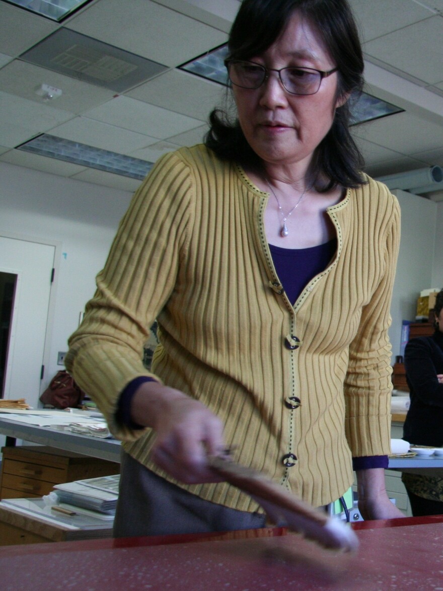 Conservator Xiangmei Gu works at a red lacquer table in the gallery's conservation lab.