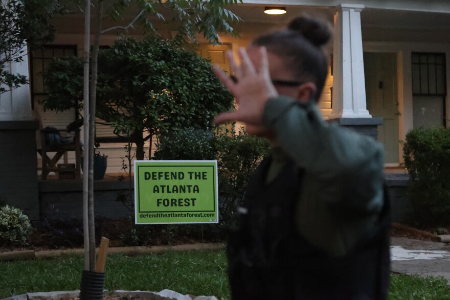 A law enforcement officer covers her face after marching through a gathering of activist at Brownwood Park who oppose the Atlanta Public Safety Training Center that protesters refer to as "Cop City," just as a vigil for killed activist Manuel "Tortuguita" Terán was set to begin, informing them the park will be closed at 11PM in Atlanta, Georgia, U.S., June 24, 2023.