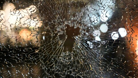 A window is shown shattered with lights reflecting onto the glass.