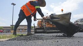 A man shovels hot asphalt during a parking lot