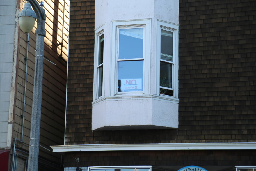 A "No on X" sign in a window above a shop