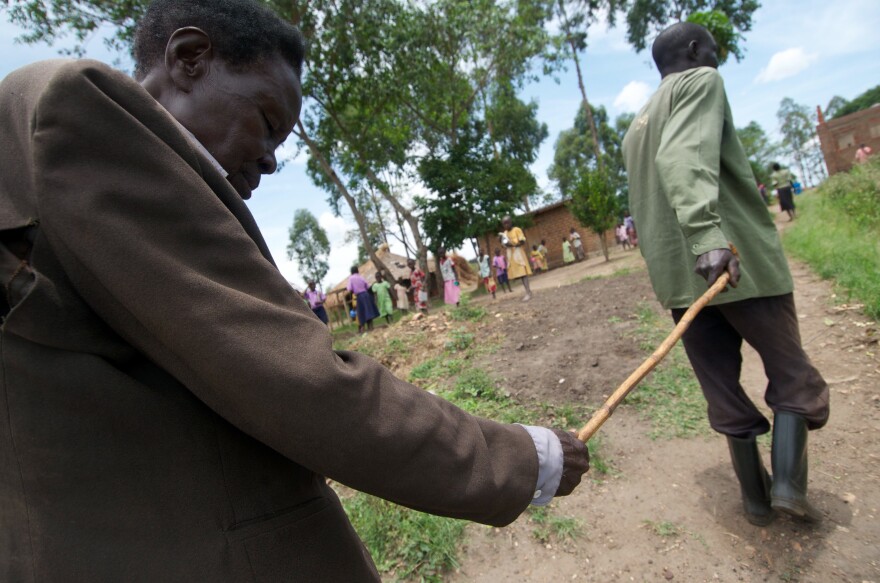 Oromdi Yallo Lambert leads his blind father, Fabiano Olur, who lost his sight to river blindness, in Nebbi district, Uganda.