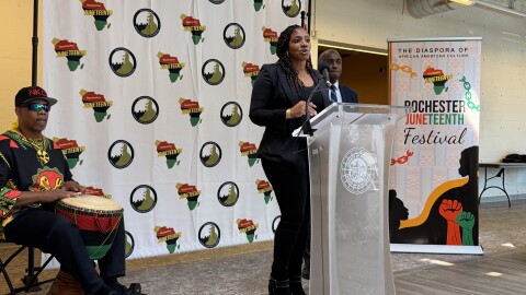 Nikia Washington, coordinator of the Rochester Juneteenth Festival, delivers closing remarks during a ceremony announcing this year's event. Behind her to the right is Simeon Banister, president and CEO of the Rochester Area Community Foundation and leader of The Greater Rochester Martin Luther King Jr. Commission, and drummer Shenuti Nehast Kawaida.
