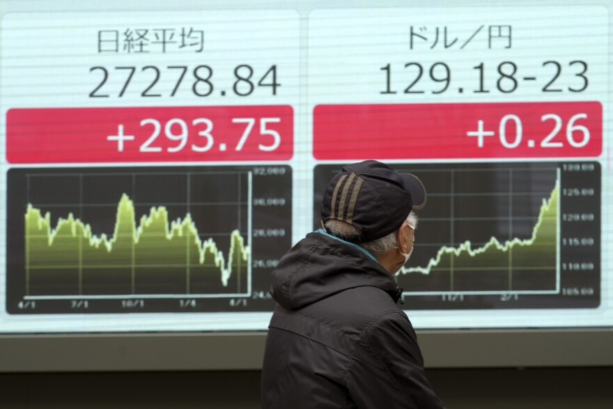 A man wearing a protective mask looks at an electronic stock board showing Japan's Nikkei 225 index and U.S. dollar/Japanese Yen exchange rate at a securities firm Wednesday, April 20, 2022, in Tokyo. (AP Photo/Eugene Hoshiko)