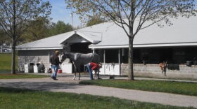Handlers shoe a horse near a barn at Keeneland Race Track
