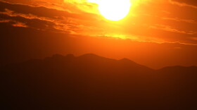 The setting sun illuminates the clouds over the Rocky Mountains.