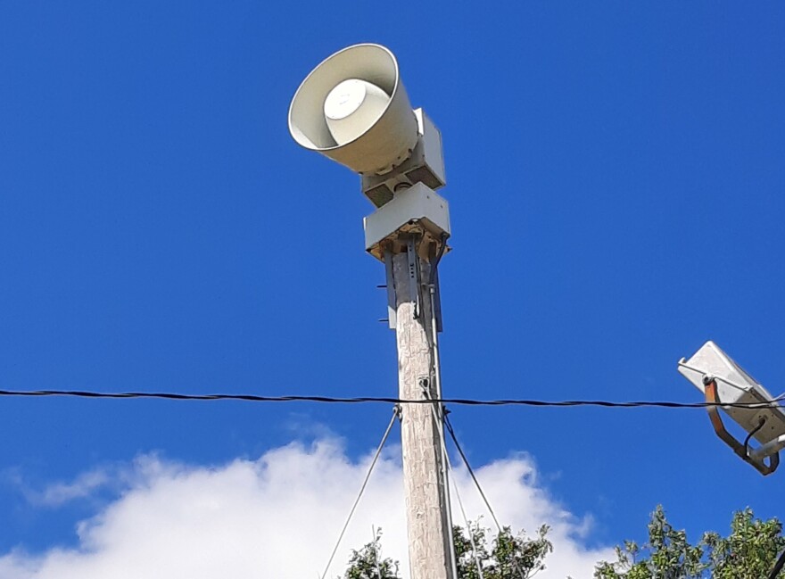 Photo of a storm siren with a blue sky background.