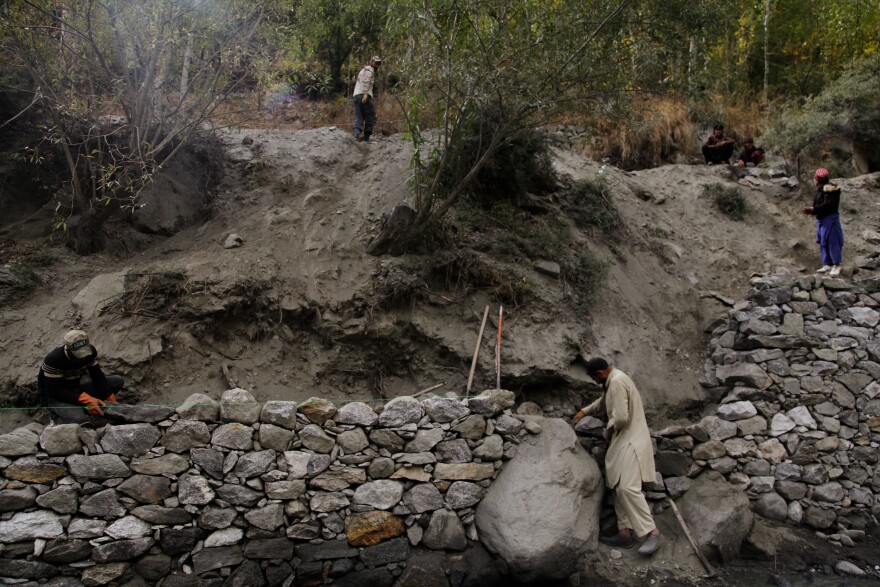 Workers build stone walls along parts of the riverbank in Harchi Valley, hoping that will prevent future glacial floods from washing away more land.