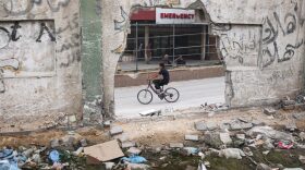 A Palestinian youth bikes past the damaged Nasser Hospital in Khan Yunis in the southern Gaza Strip amid the ongoing conflict between Israel and the Palestinian militant group Hamas.
