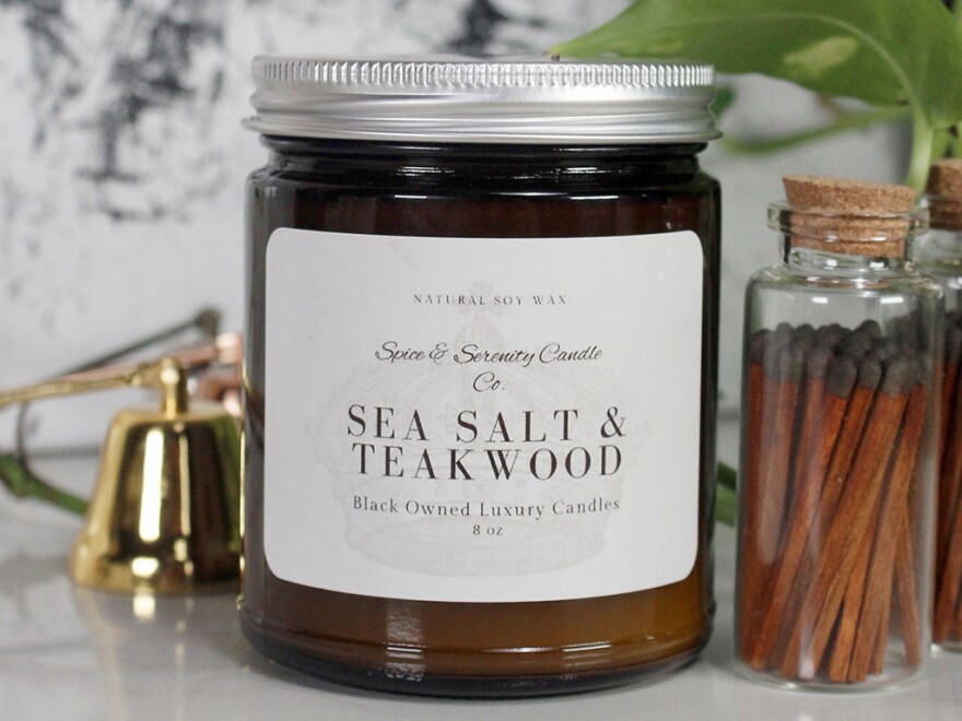 A picture of an 8-ounce candle. The amber glass bares a sticker that reads: Natural Soy Wax Spice & Serenity Candle Co. Sea Salt & Teakwood