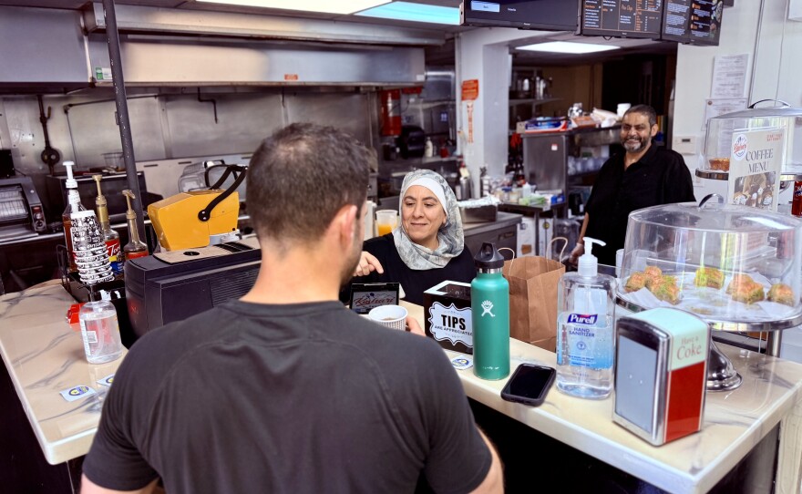 Customer buying lunch from Koshari Shack interacts with owners Yahia Sewellam and his wife Fatin Ittayem