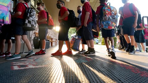 Wearing masks to prevent the spread of COVID-19, elementary school students line up to enter school for the first day of classes in Richardson, Texas, Tuesday, Aug. 17, 2021.