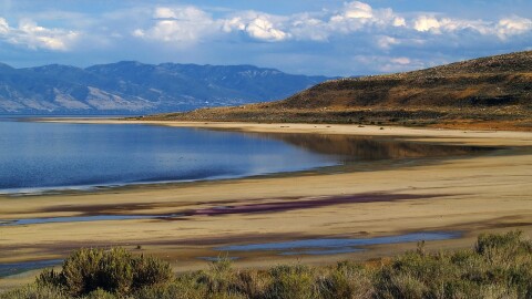 A low lake surrounded by mountains and greenery