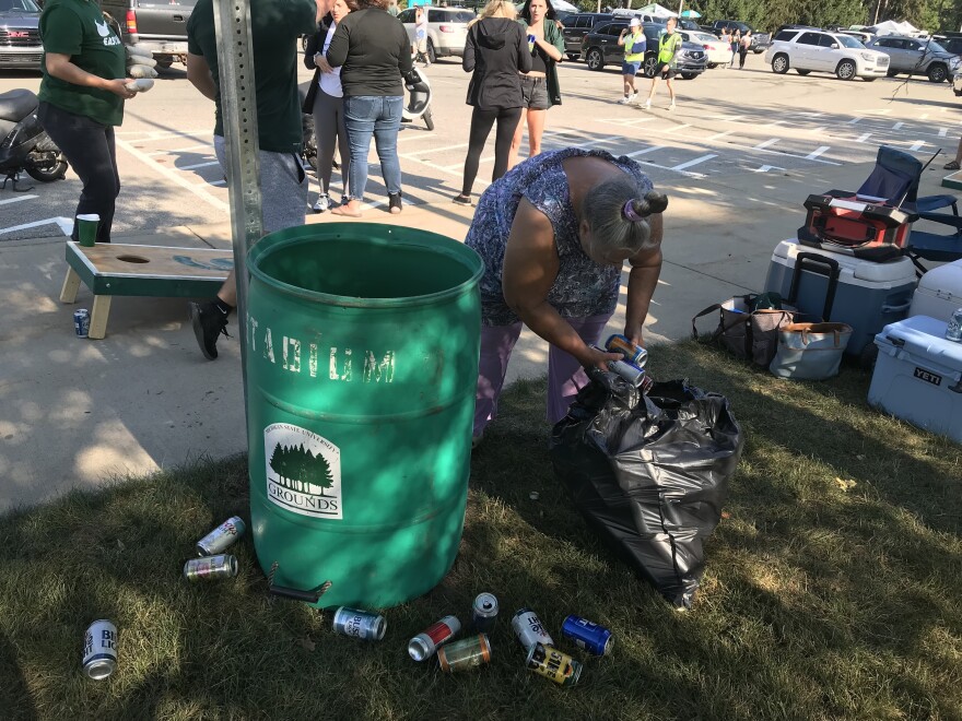 Holly Rutter collects cans from tailgaters on the campus of Michigan State University in East Lansing on Sept. 11, 2021. People in Michigan can get 10 cents for each can or bottle they return to a store.