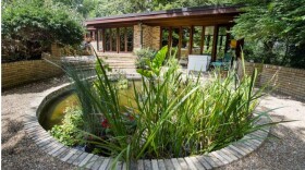 Picture of a mid-century modern house with a circular pond in front of it.