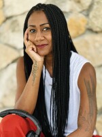 person in a white tank top sitting with one hand on their chin.
