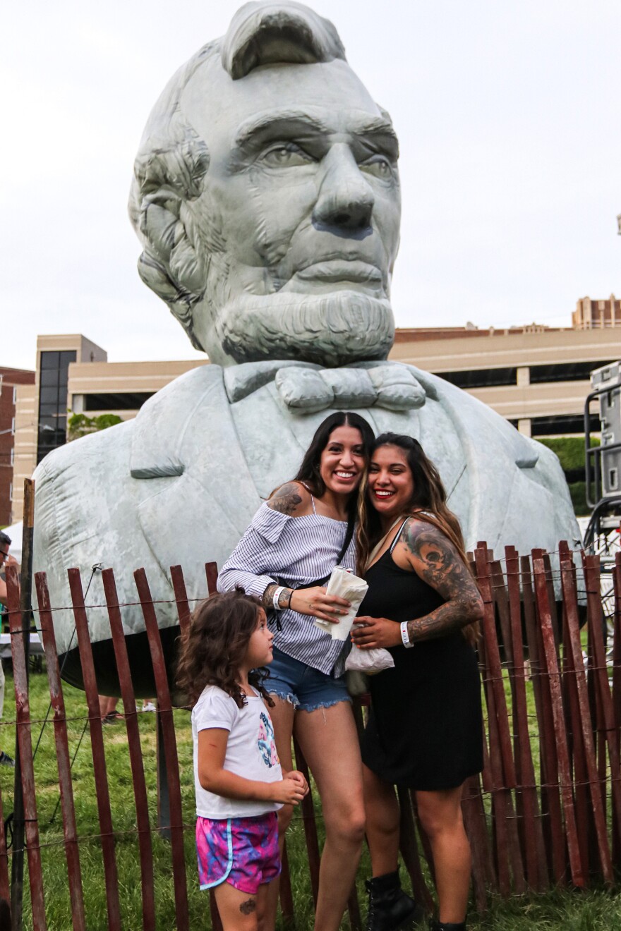 Festival-goers pose next to the Abe Stage's inflatable head of Abe Lincoln.