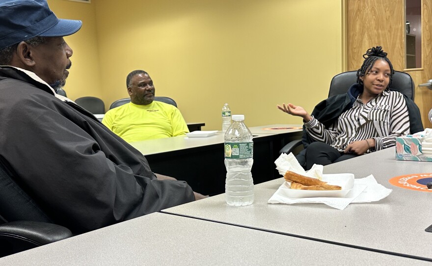  Three Black individuals, two male and one female, shown having a discussion.