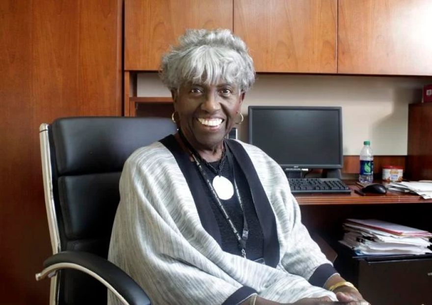 A woman poses in an office chair in front of a computer.